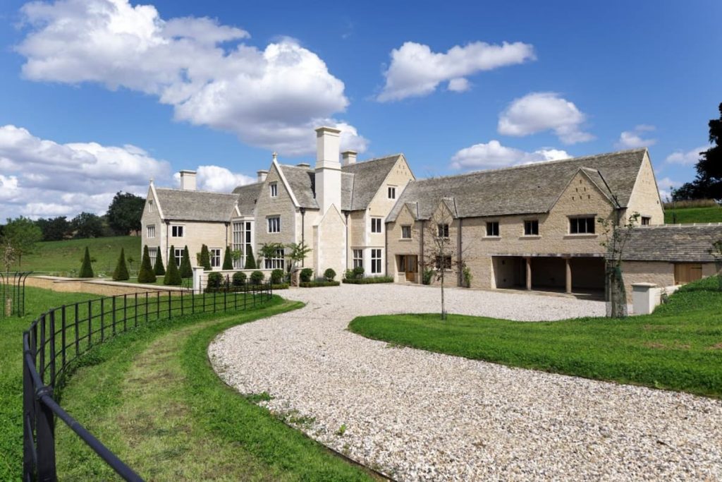 A driveway level photo of a new build private residence near Chipping Norton by Cranatt Construction. The property has green space around it and it's a sunny day with clouds in the sky.