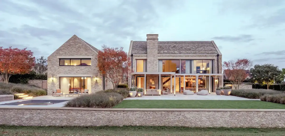 Luxury contemporary Cotswold stone home with large windows, terrace seating, and landscaped garden.
